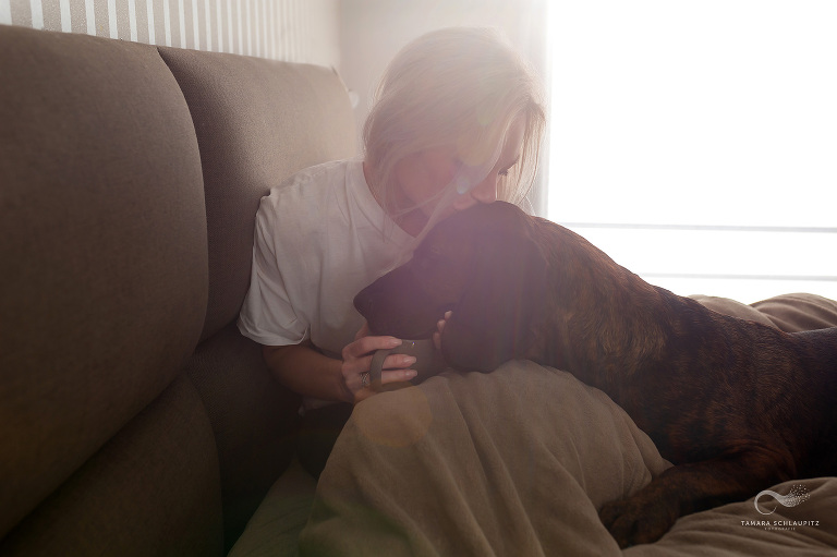 Frauchen mit Tasse Kaffee in der Hand kuschelt morgens mit ihrem Jagdhund im Bett